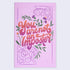 A flat lay view of a pink notebook with a floral design and the text &